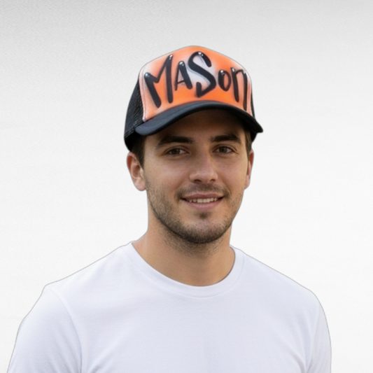 Man wearing a black trucker cap with 'Mason' airbrushed on it with a orange design against a plain background
