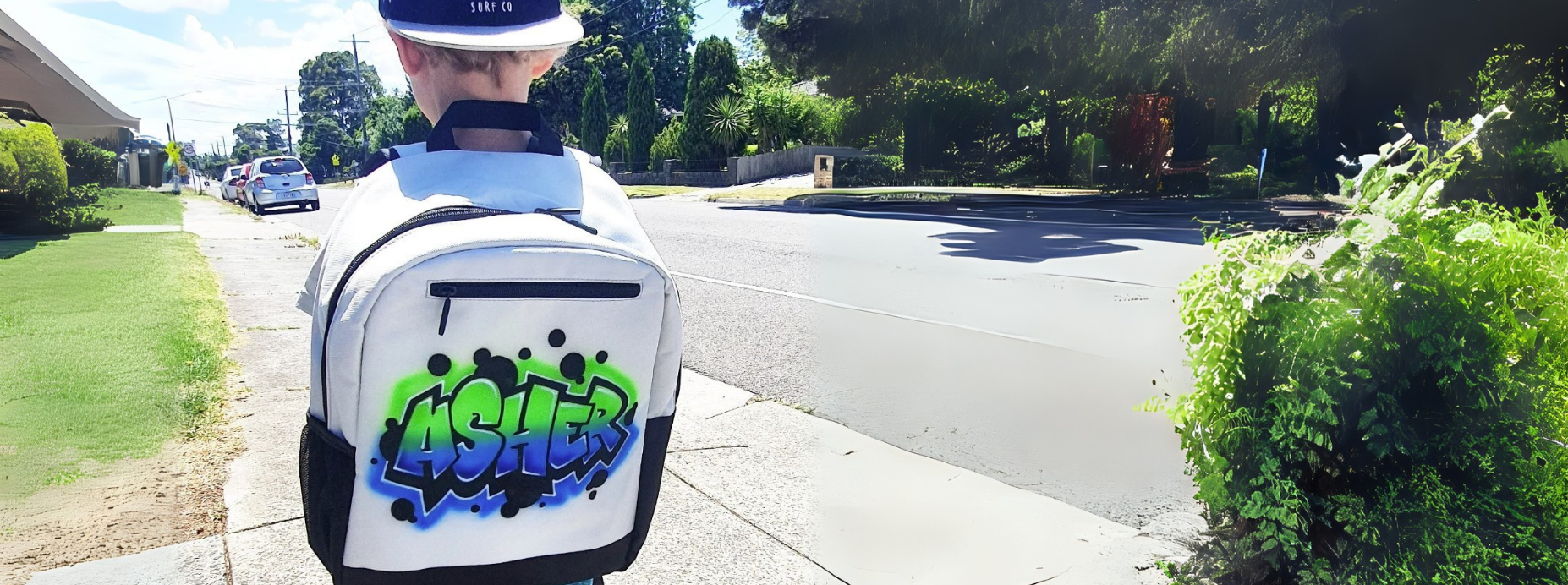 Child wearing a backpack with a airbrush graffiti name on a sidewalk.