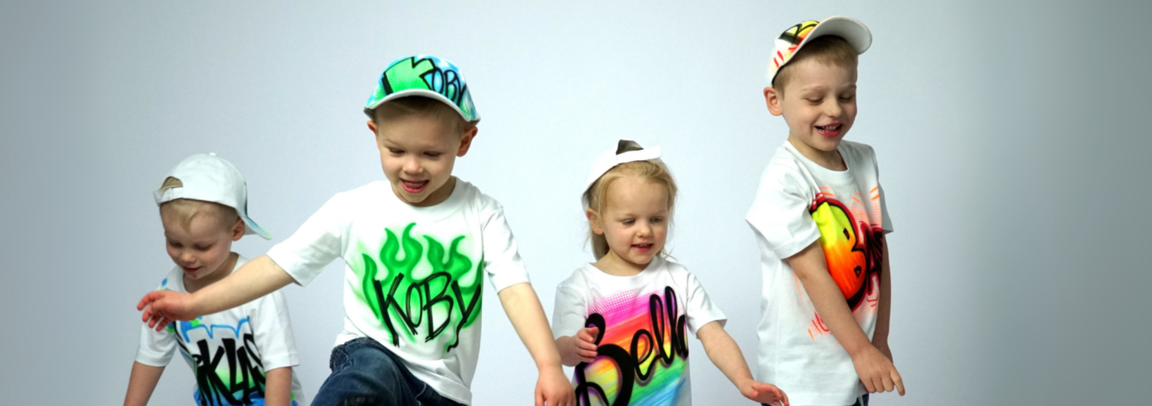 Four children wearing colorful Airbrush t-shirts and hats on a gray background