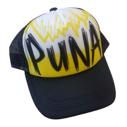 Black trucker cap with 'PUNA' airbrush text with a yellow design on a white background