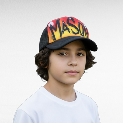 Child wearing a colorful airbrush trucker cap with 'MASON' on a flame background