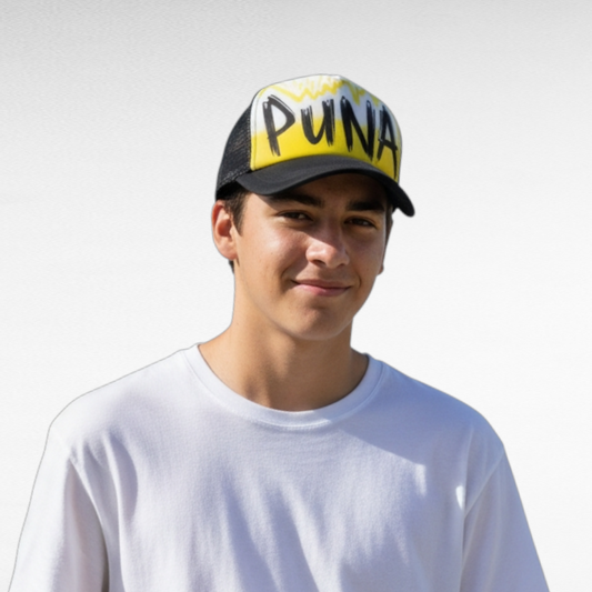Person wearing ablack trucker cap with 'Puna' airbrushed with a yellow design against a plain background