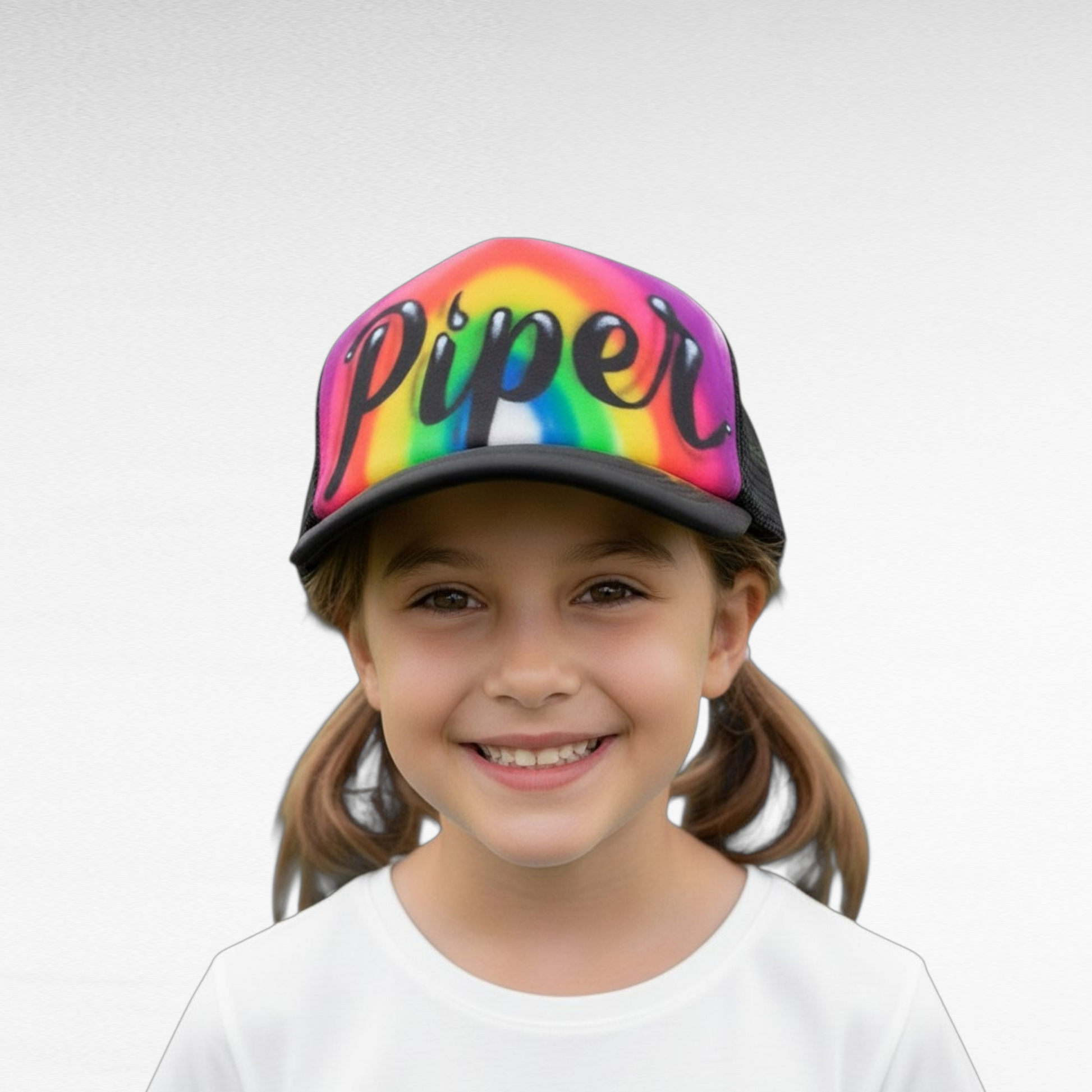 Child wearing a airbrush rainbow cap with 'Piper' on a white background