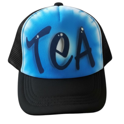 Black trucker cap with 'TEA' text airbrushed with a blue design on a white background