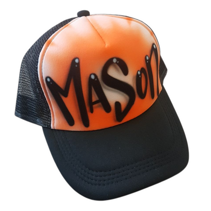 Black trucker cap with 'MASON' airbrushed on it with a orange design against a white background